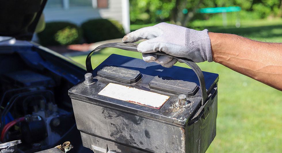 Man taking a car battery out of a truck